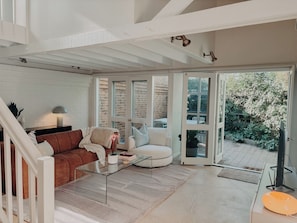 A modern living room with a glass coffee table, a brown sofa, and a white armchair.
