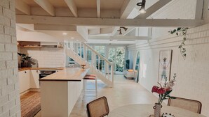 Une cuisine moderne dotée d’un îlot central, d’un coin repas avec une table ronde et d’un escalier menant à un niveau supérieur.