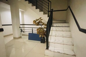 A staircase with black handrails, a potted plant, and a blue bench.