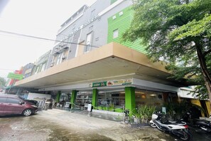 A multi-story building with a green and beige facade, a covered entrance, and a visible sign indicating a 50% discount.