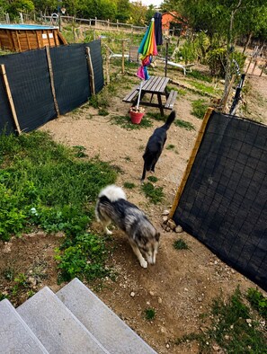 A fenced backyard with a wooden deck, a picnic table, and a basketball hoop. - L'élixir, a cozy bed-and-breakfast in Ardèche, surrounded by nature, where you can bring your dog (Sécheras)