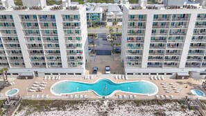 A high-rise hotel with multiple balconies, a central pool, and a parking area. - Ocean House 2701 Beachfront (Gulf Shores)