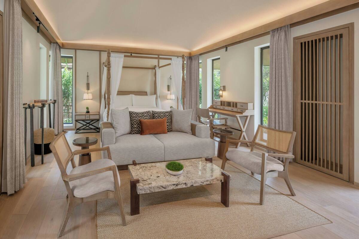 A spacious living room with a sofa, chairs, a coffee table, and a window with curtains.