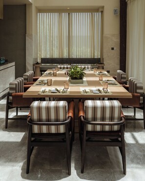Un comedor con una mesa larga, sillas a rayas y un centro de mesa con planta en maceta.