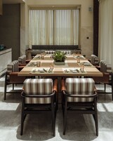 Un comedor con una mesa larga, sillas a rayas y un centro de mesa con planta en maceta.