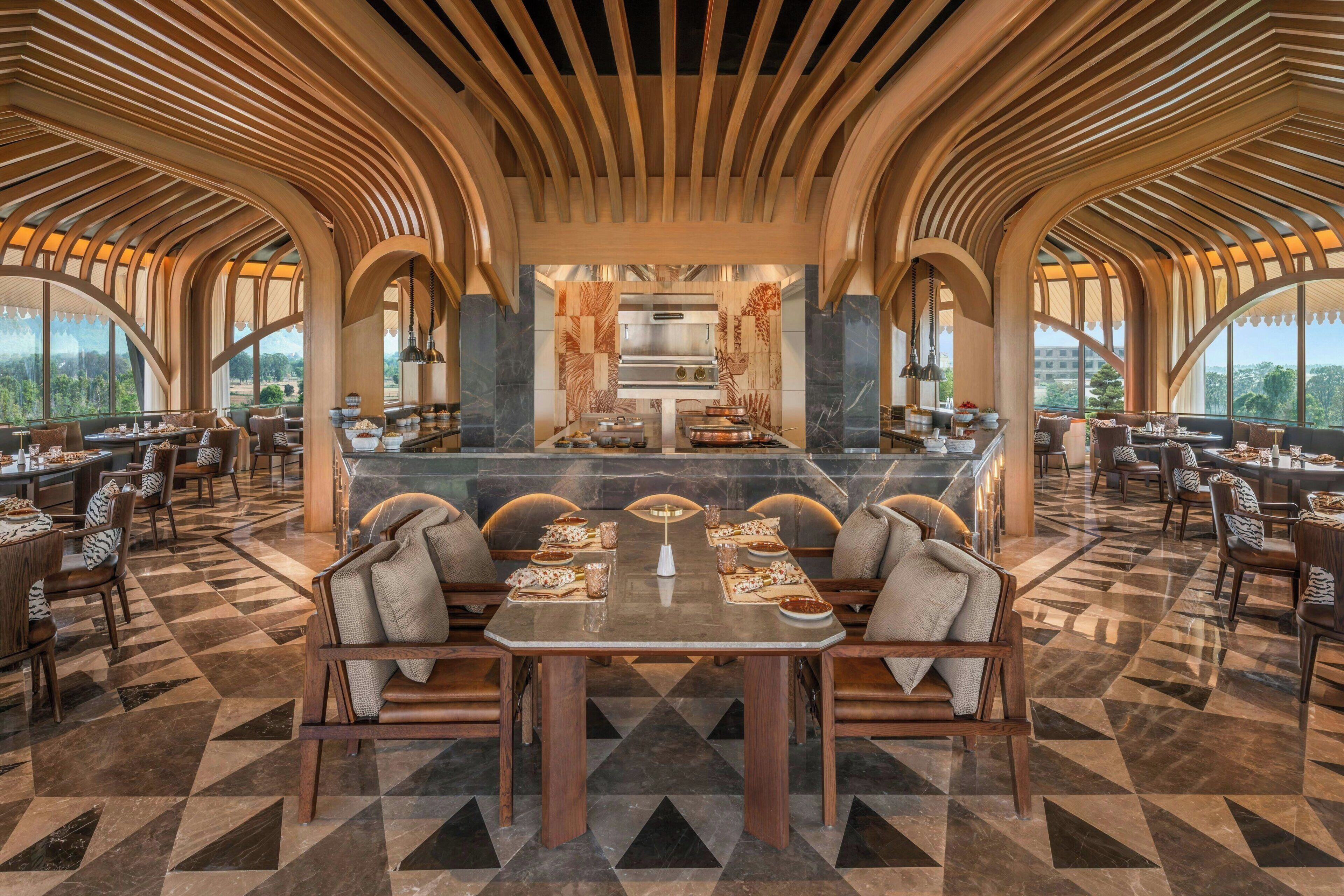 A spacious dining area with a central island, high ceilings with wooden beams, and a view of the outdoors through large windows.