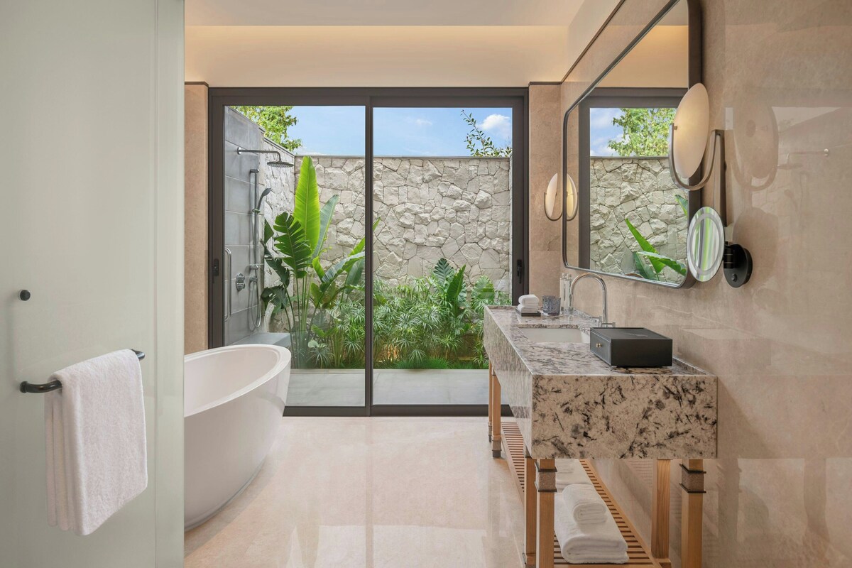 A modern bathroom with a freestanding bathtub, a marble vanity, and a large mirror.