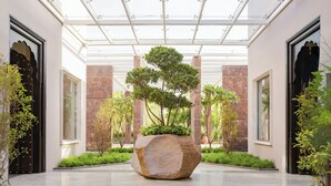 A modern indoor space with a central stone planter, glass ceiling, and stone walls. - JW Marriott Ranthambore Resort & Spa (Sawai Madhopur)