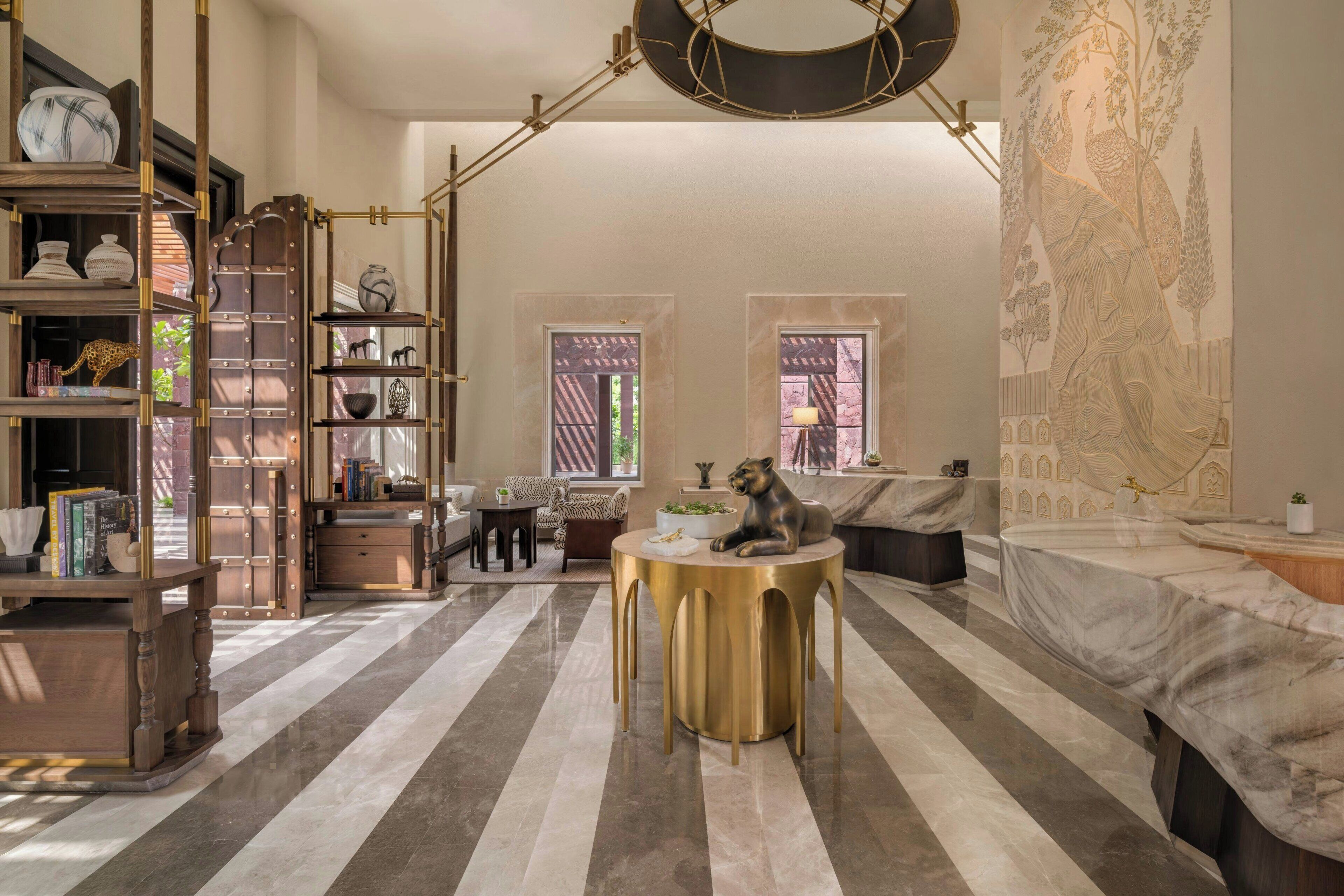 A spacious room with a striped floor, a round gold table, a sofa, and a large tapestry.