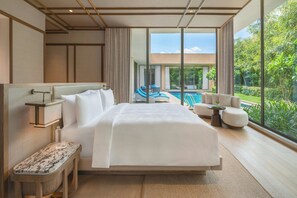 Une chambre d’hôtel dotée d’un grand lit, d’un coin salon avec vue sur la piscine et d’un balcon donnant sur la verdure.