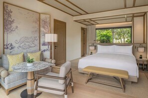 A hotel room with a bed, a seating area with a table and chairs, a large window, and artwork on the walls. - JW Marriott Ranthambore Resort & Spa (Sawai Madhopur)