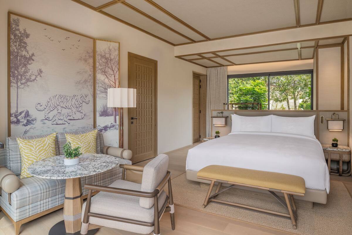 A hotel room with a bed, a sofa, a round table, and a bench.