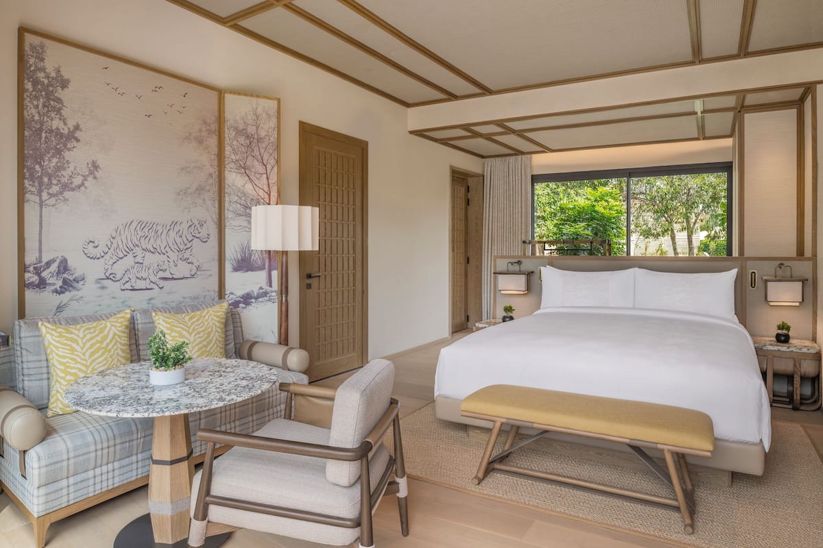 Una habitación de hotel con cama, sofá, mesa redonda y banca.