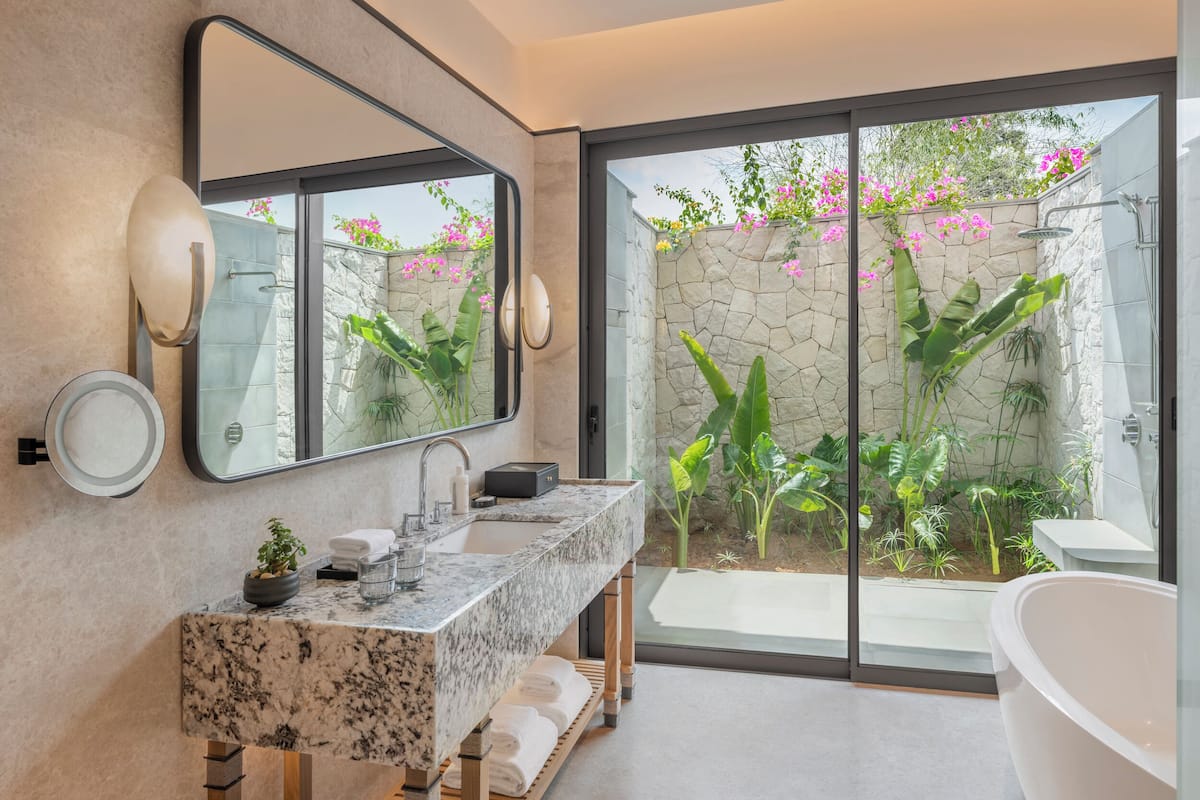 Un baño moderno con un lavamanos grande, un espejo y una bañera.