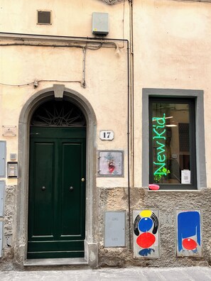 Ein Gebäude mit einer grünen Tür, einem Fenster mit einer Neonreklame und einem Nummernschild.