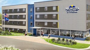 A Microtel Inn & Suites by Wyndham building with a modern design, multiple floors, and a visible entrance area with people. - Microtel Inn & Suites by Wyndham Blytheville (Blytheville)