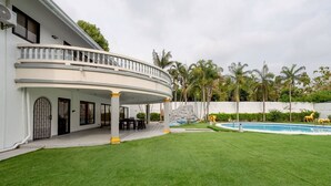 A two-story house with a covered patio, a swimming pool, and a well-maintained lawn.