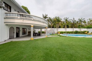 A two-story house with a covered patio, a swimming pool, and a well-maintained lawn.