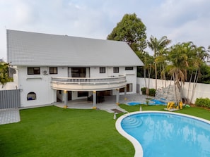 Une maison à deux étages avec une piscine, un patio couvert et une cour clôturée.