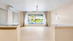A spacious room with a large window, a ceiling fan, and a view of a garden with a yellow elephant statue.