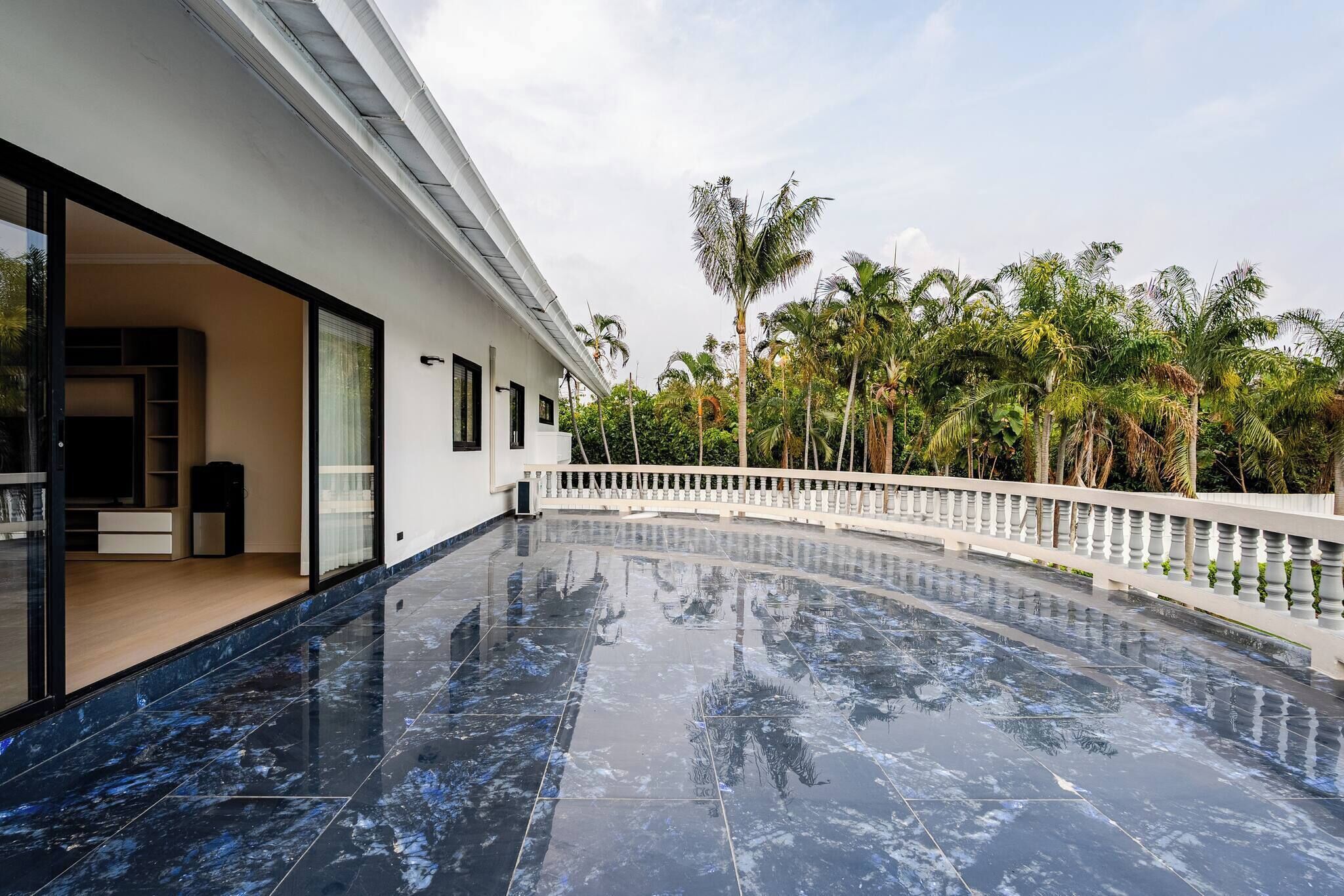 A modern building with a curved glass facade, a reflective marble floor, and a white balcony railing.