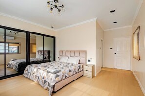 Une chambre à coucher avec un grand lit, une table de chevet, un miroir et une porte coulissante.