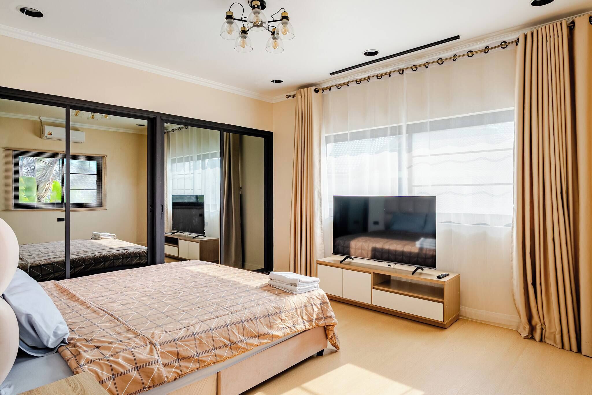 Un dormitorio con cama, televisión y puertas correderas.