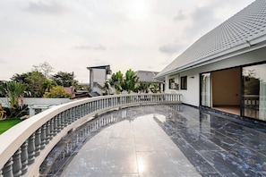 A modern building with a curved balcony, a tiled floor, and a clear sky.