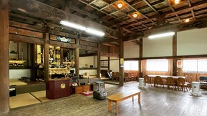 Ein geräumiges Zimmer mit Holzböden, einer Holzbalkendecke und einer Sitzbank. Ein Tisch mit Stühlen steht ebenfalls im Raum.
