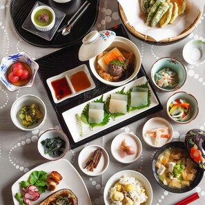 A variety of dishes arranged on a table, including a bowl of soup, a plate of sashimi, and several small dishes with condiments.