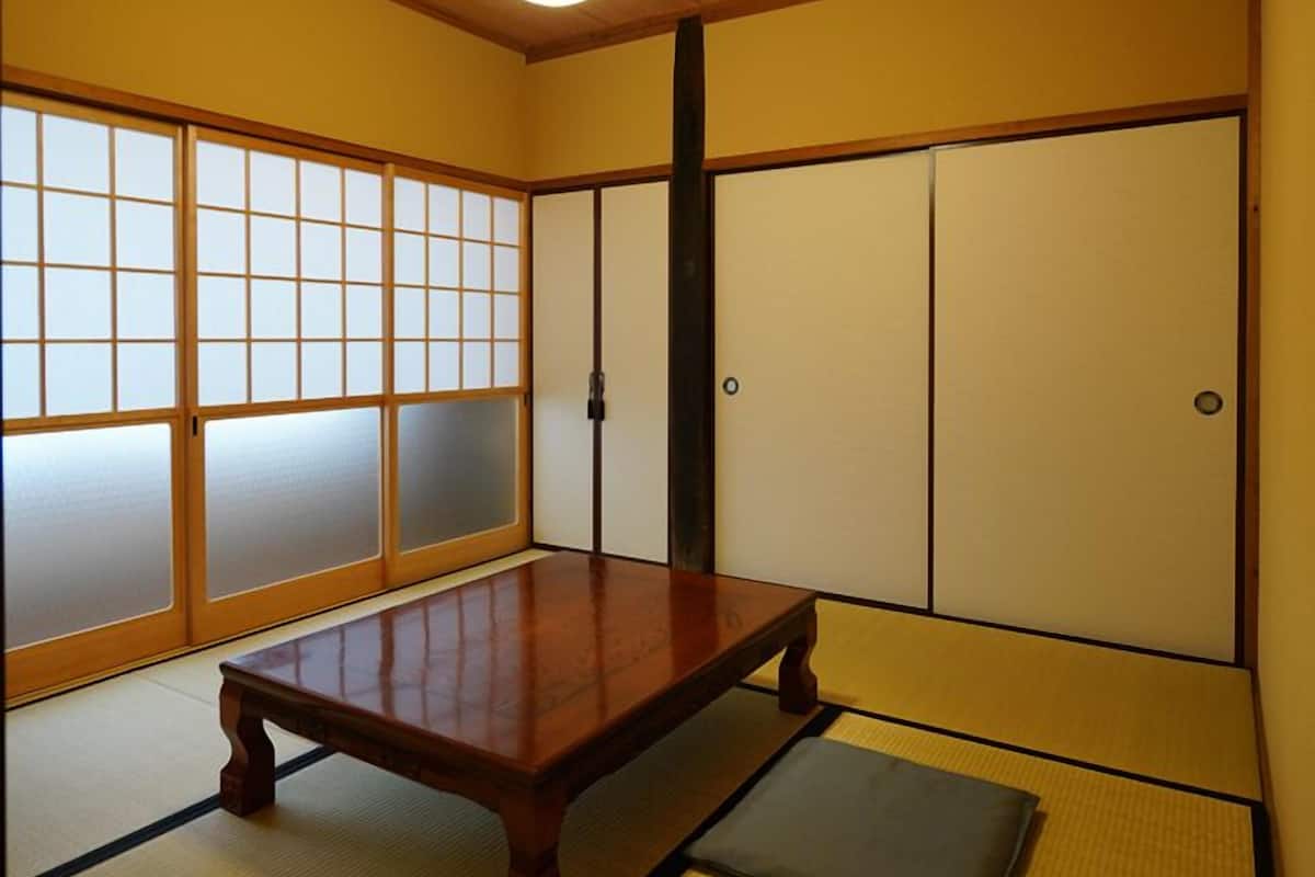 Perinteinen japanilainen huone, jossa on tatamimatto, matala puupöytä, liukuvat shoji-ovet ja kattovalaisin.