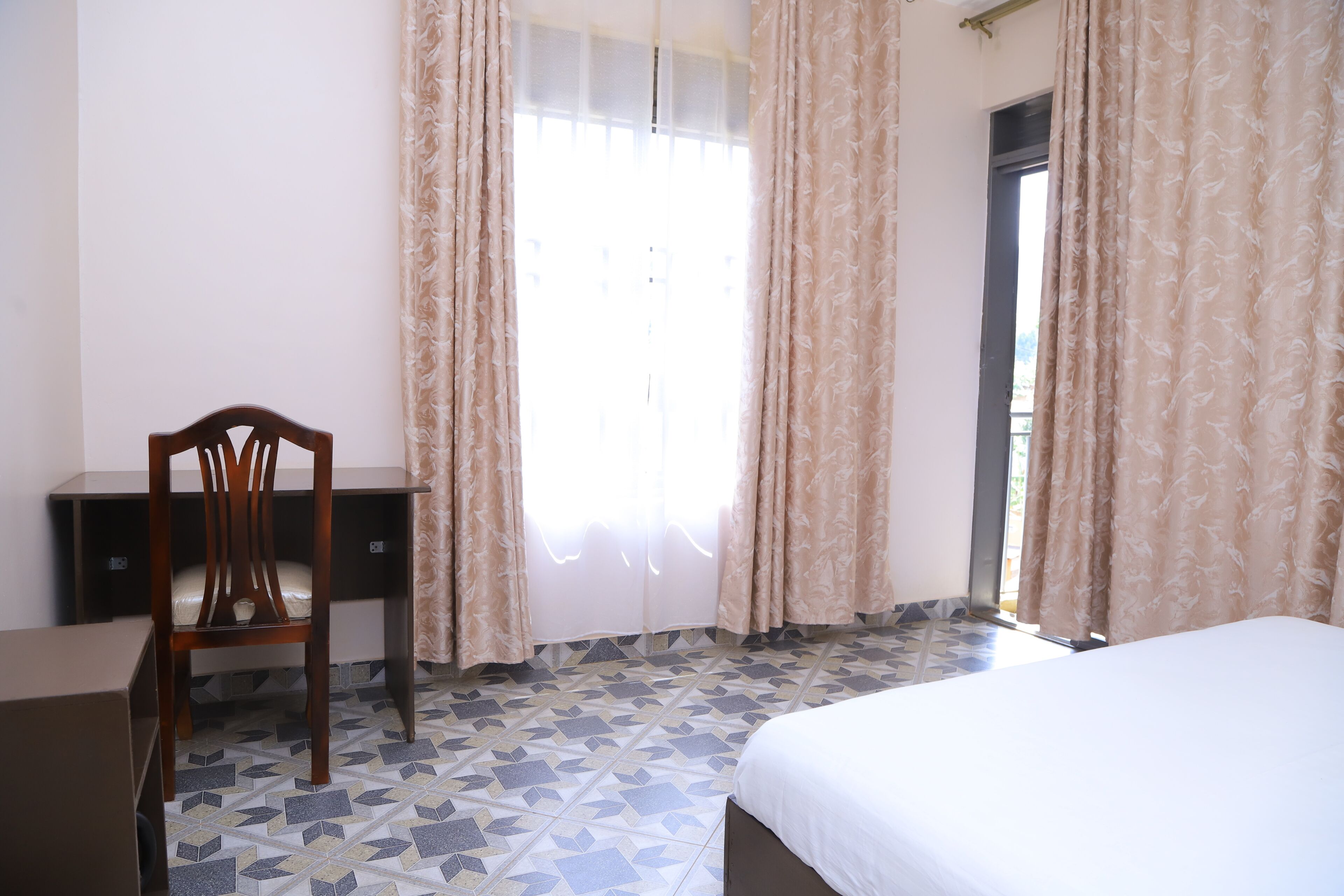 A bedroom with a bed, a desk, and a chair.