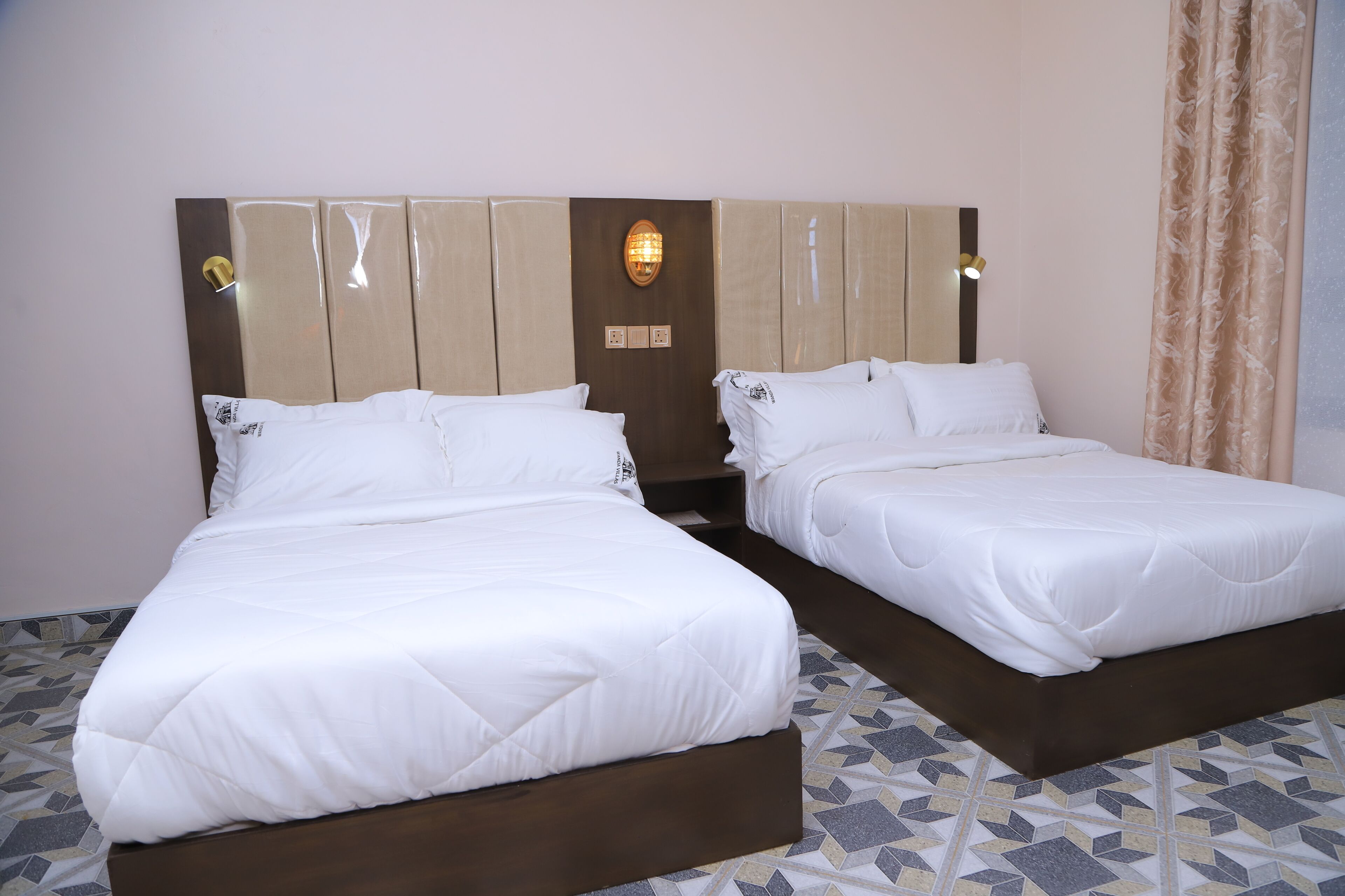 A double bed with a wooden headboard, a bedside table, and a wall-mounted light fixture.