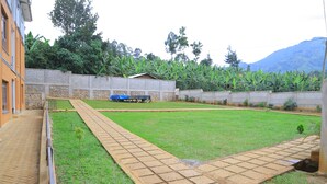 A courtyard with a paved walkway, a small lawn, and a building with a stone wall.