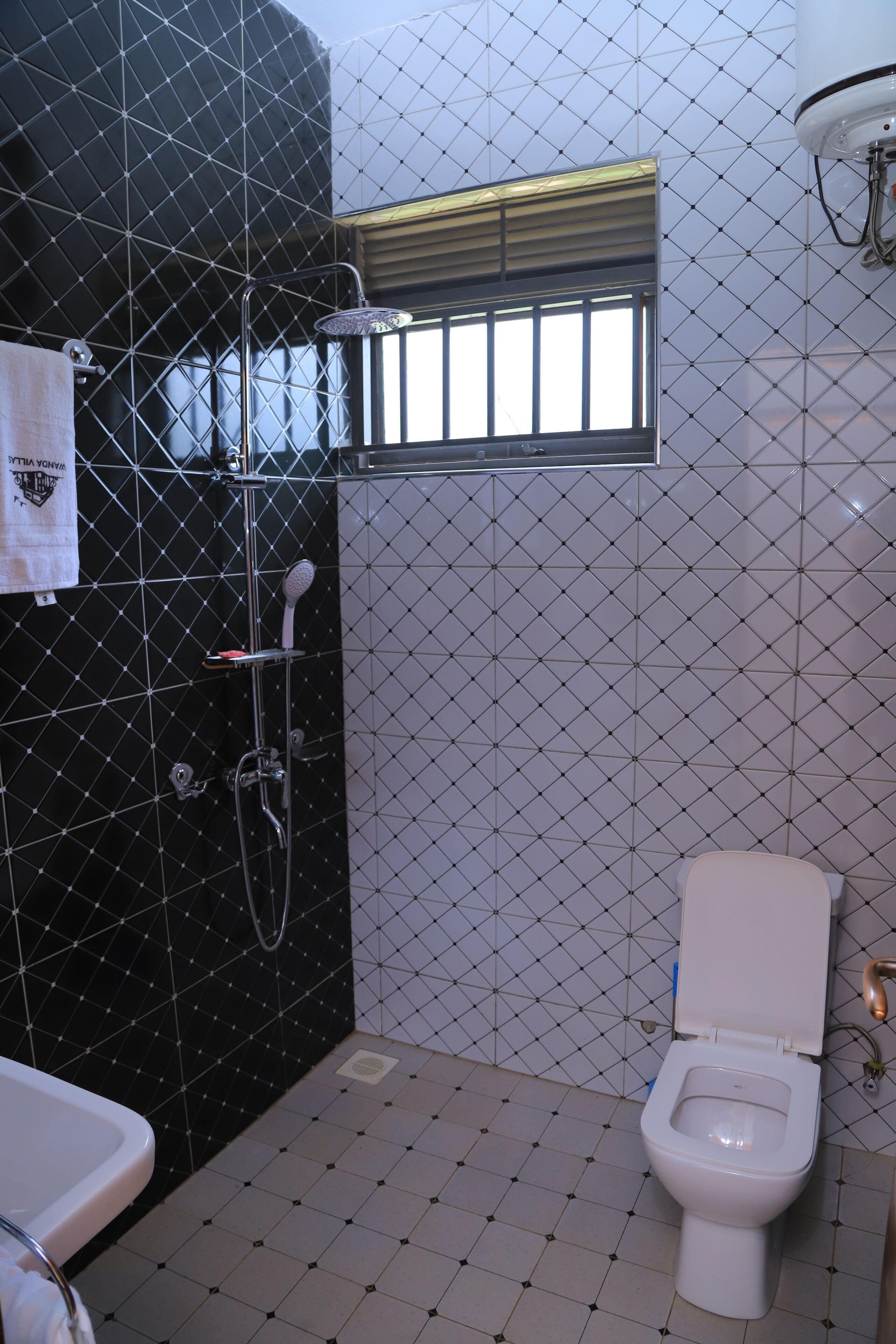 A bathroom with a black tiled wall, a white toilet, and a shower area.