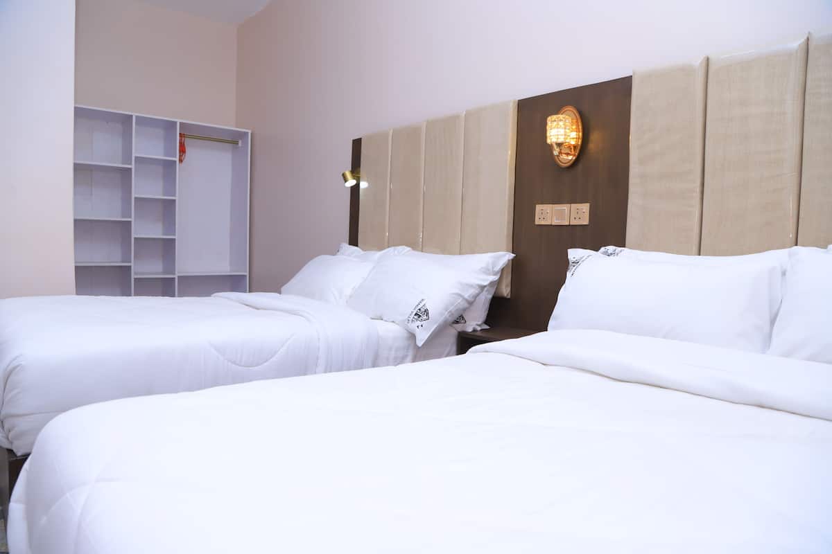Una habitación de hotel con dos camas, un armario y una lámpara fijada a la pared.