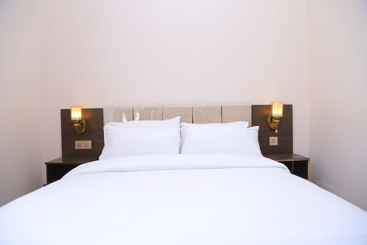 Una habitación de hotel con cama, dos lámparas de noche y una mesita de noche.