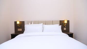 Una habitación de hotel con cama, dos lámparas de noche y una mesita de noche.