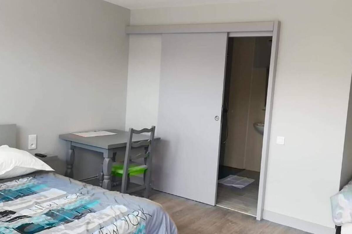 A bedroom with a bed, a desk, and a wardrobe.