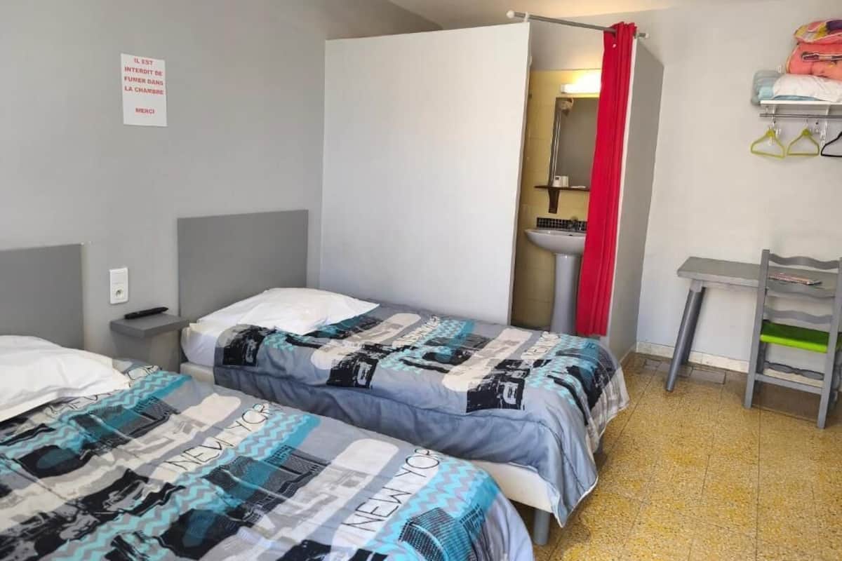 A room with two beds, a sink, and a mirror.