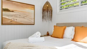 A bedroom with a bed, a hanging light fixture, a painting, and a window with a view. - Welcome to Pineapple Cottage, a relaxed Byron Bay retreat designed for easy coastal living. (Byron Bay)