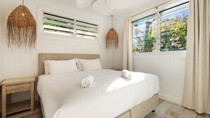 Un dormitorio con cama, mesitas de noche y una ventana con persianas.