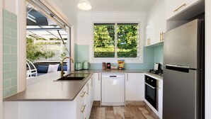 Una cocina moderna con un refrigerador de acero inoxidable, armarios blancos y un ventanal con vistas a zonas verdes.