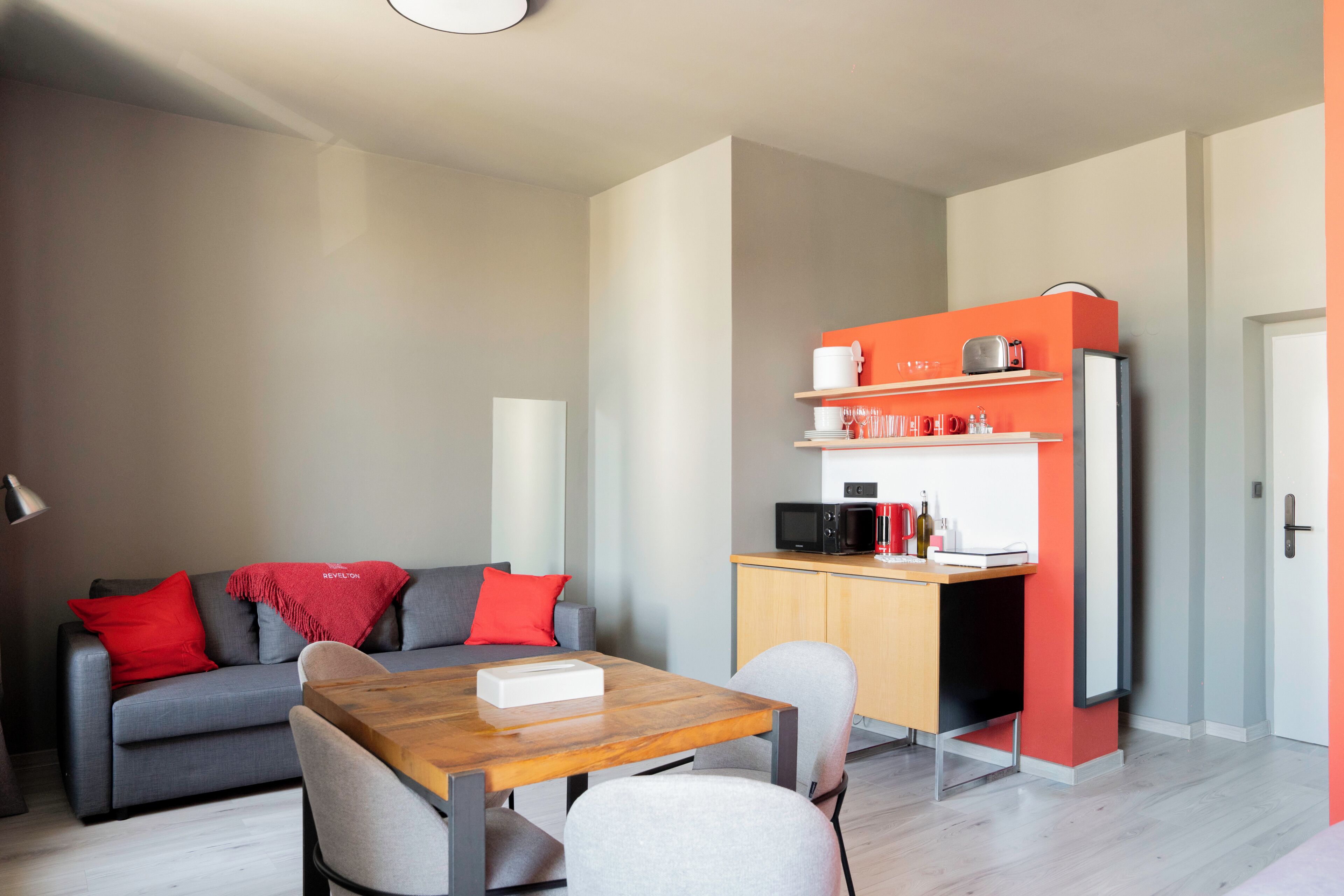 Een moderne woonruimte met een bank, een eettafel en een kitchenette.