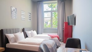 A hotel room with two beds, a desk, a TV, and a window with curtains. - Revelton Ostrava (Ostrava)