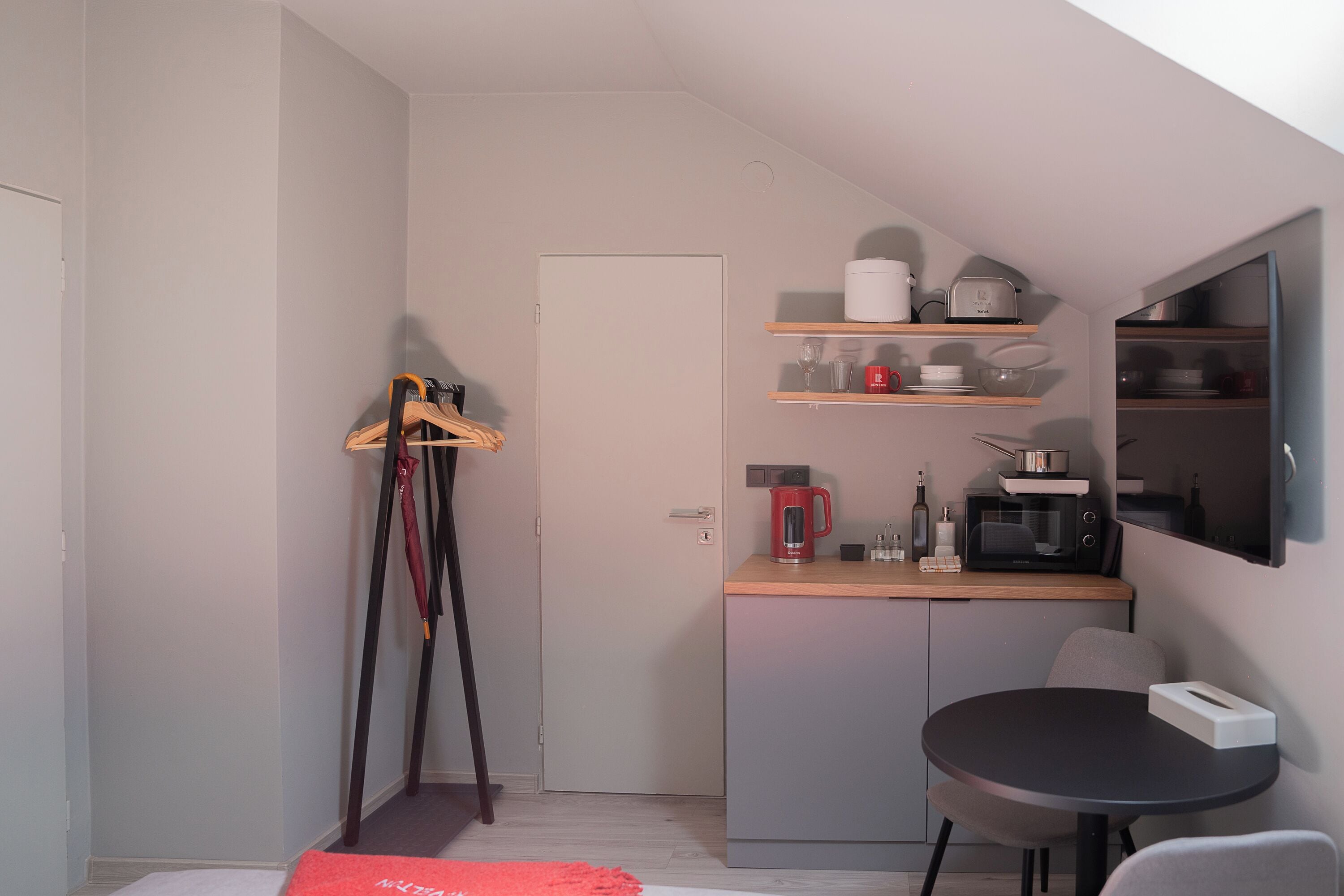 A compact kitchen with a microwave, coffee maker, and shelves above the counter.