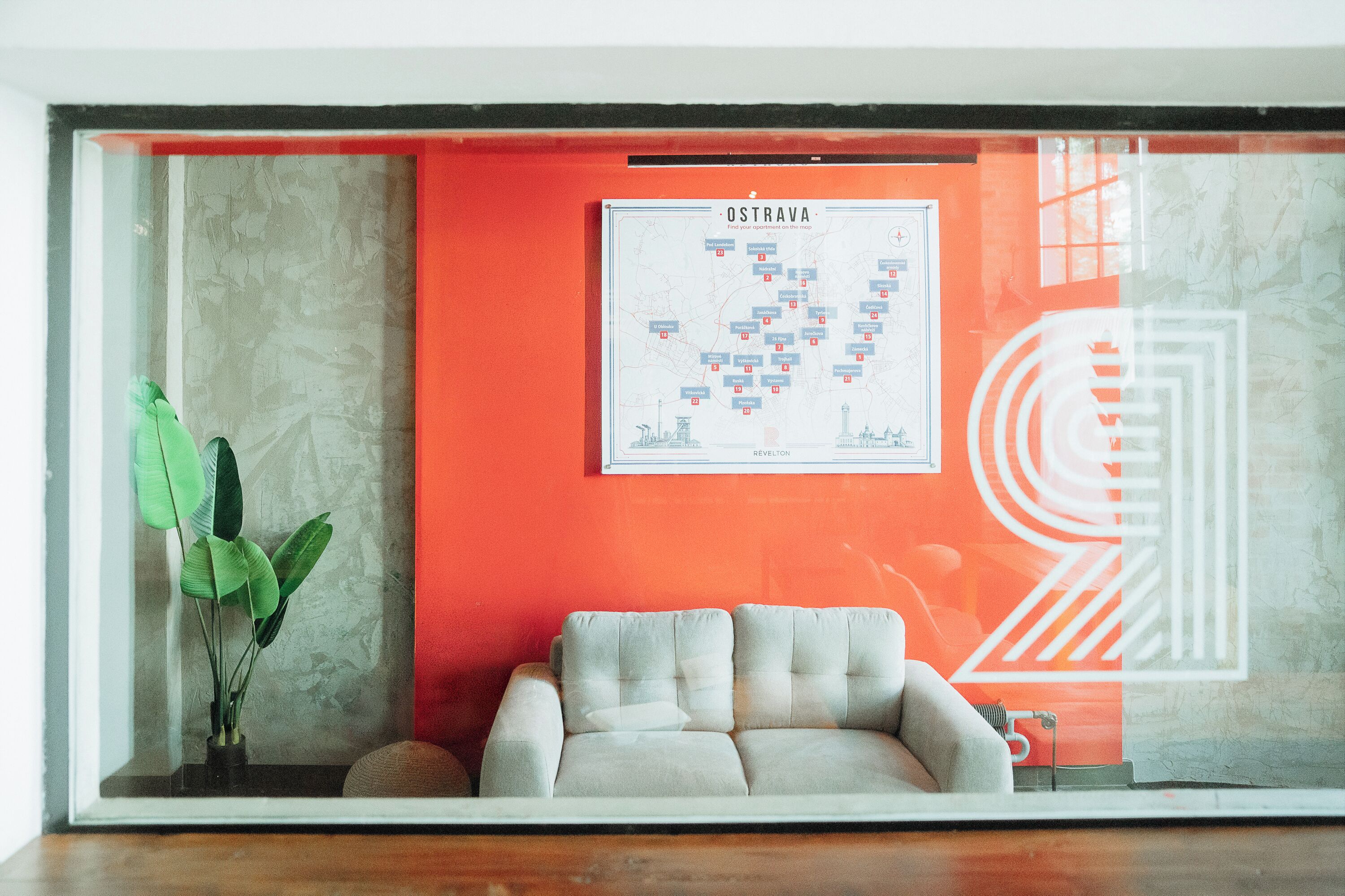 Een kamer met een bank, een kaart aan de muur en een plant.