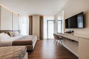 A modern hotel room with a bed, a desk, a chair, and a television.