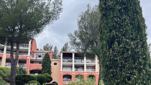 A multi-story building with balconies, surrounded by well-maintained greenery and a clear sky. - Studio with balcony, sea & golf view, swimming pool, parking-Hameau Cap Esterel (Saint-Raphaël)