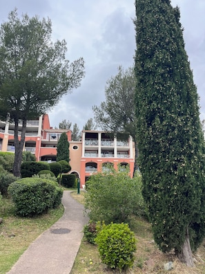 A multi-story building with balconies, surrounded by well-maintained greenery and a clear sky. - Studio with balcony, sea & golf view, swimming pool, parking-Hameau Cap Esterel (Saint-Raphaël)